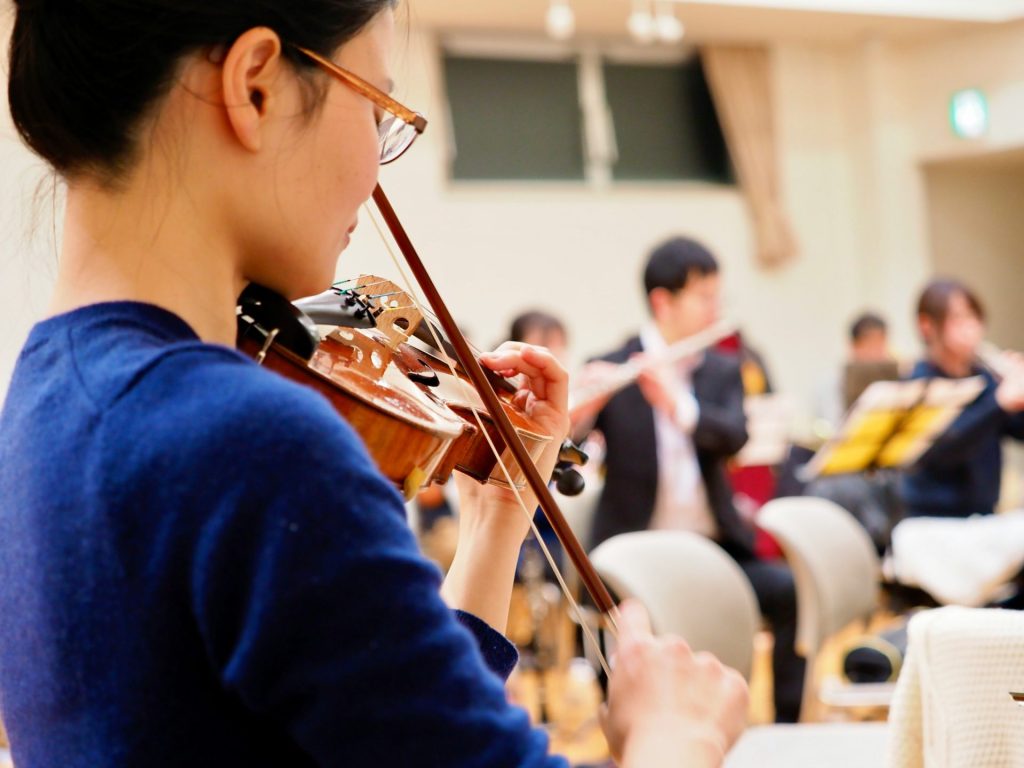 A woman playing a violin in front of a group of people